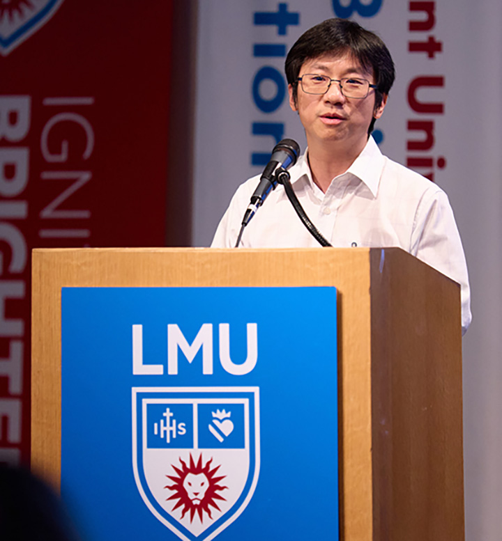 Professor Jie Xu standing in front of podium