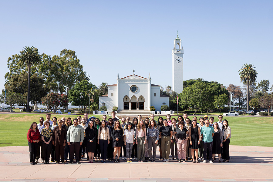 the newest faculty members pose in front of Sacred Heart Chapel